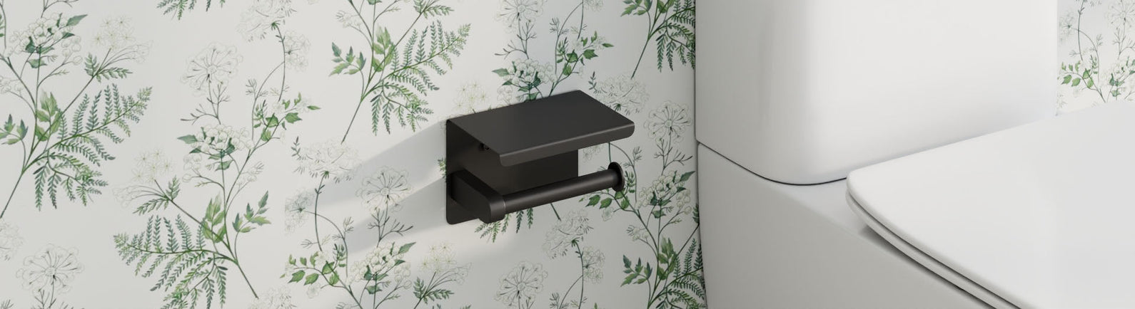 Matte-black toilet paper holder with a small top shelf mounted on a white wall with green fern motifs beside the toilet.