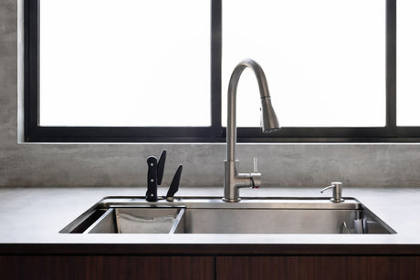 Kitchen sink with stainless steel pull-down mixer tap, double-basin design, and large window above the benchtop.