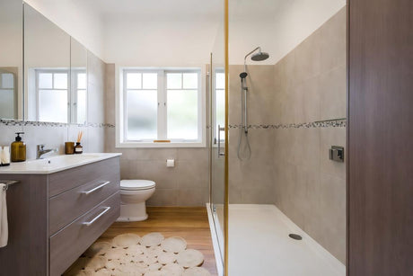 Modern bathroom with walk-in glass shower, timber vanity, frosted window, and neutral wall tiles.