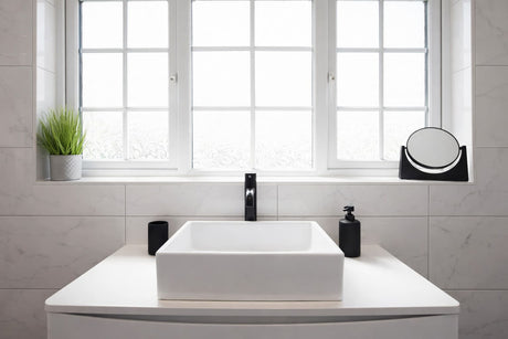 Modern bathroom vanity with square basin, black mixer tap, marble-look wall tiles, and frosted window.