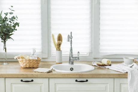 Bathroom vanity with ceramic basin, chrome mixer tap, timber benchtop, and soft natural light from window blinds.