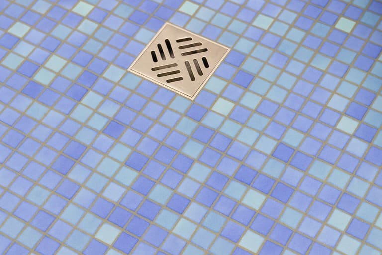 Blue mosaic tile floor with a square stainless steel shower drain.