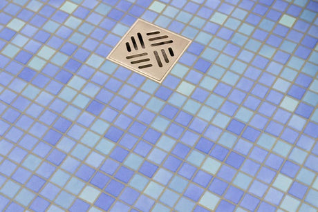 Blue mosaic tile floor with a square stainless steel shower drain.