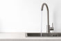 Modern kitchen sink with stainless steel gooseneck mixer tap and running water.