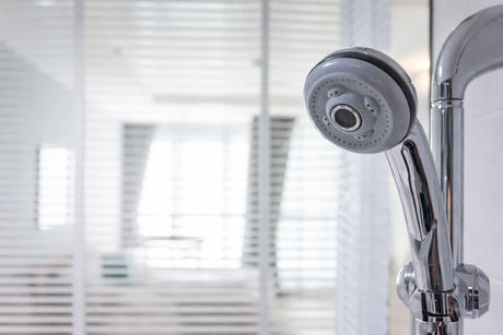 Chrome handheld shower head with adjustable spray settings in a modern bathroom.