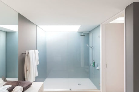 Modern minimalist bathroom with frameless walk-in shower, plush towels, and natural light.