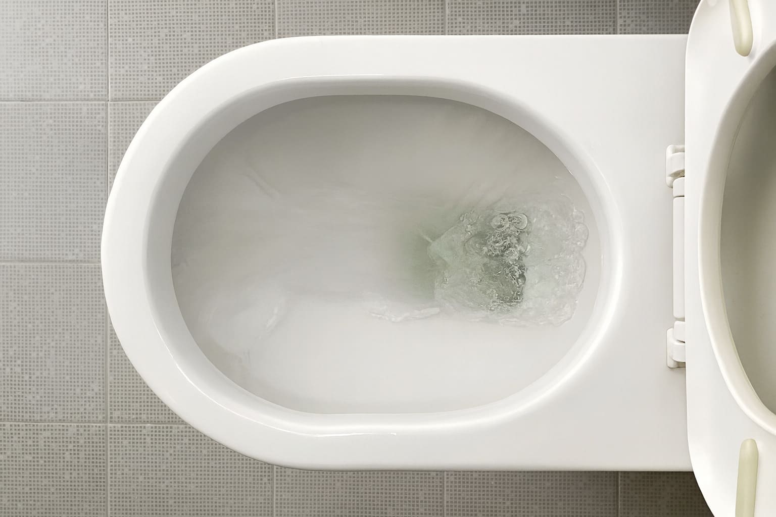Top view of a toilet bowl with water flushing