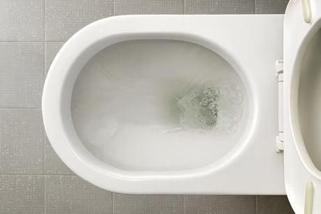 Top view of a toilet bowl with water flushing