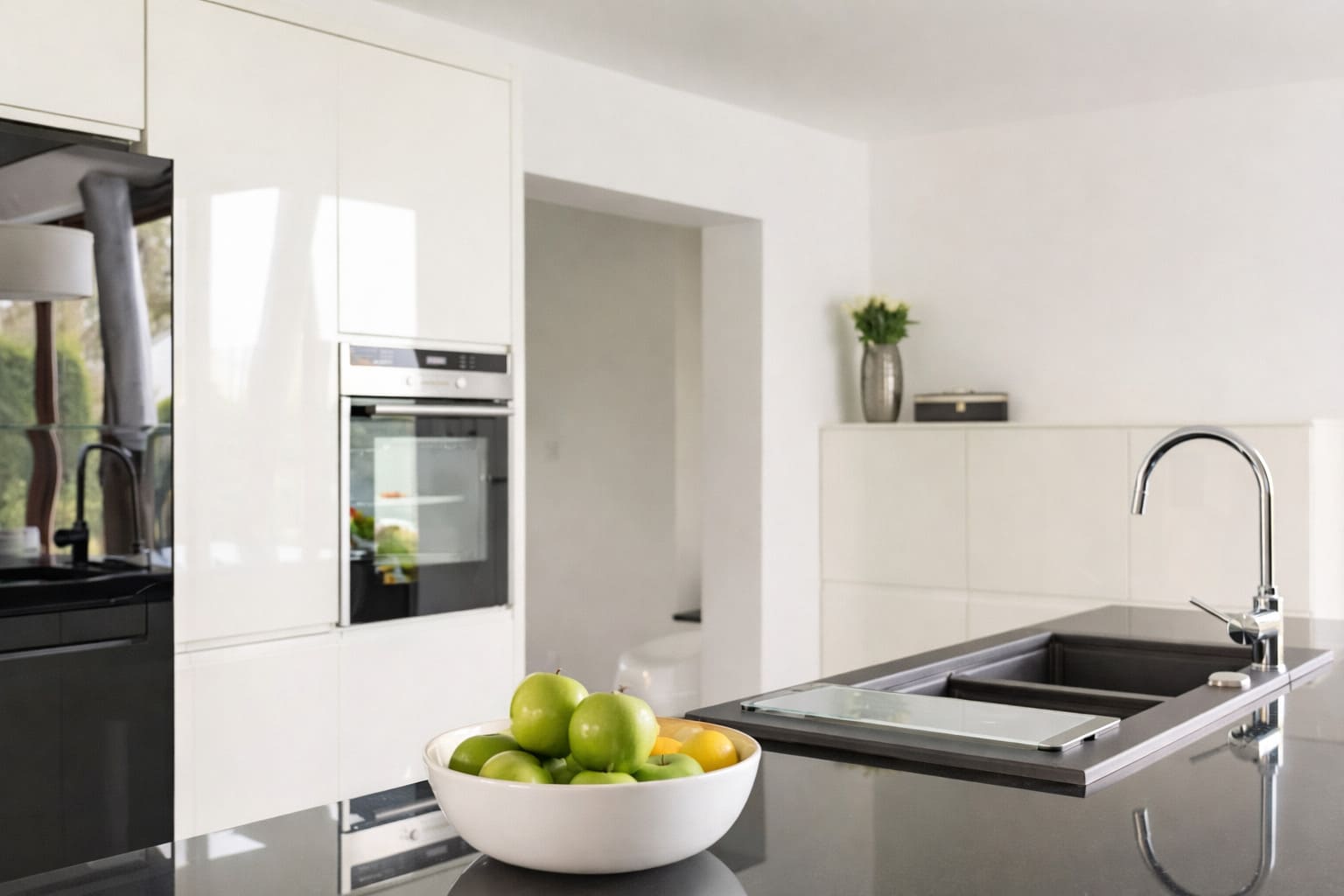 A kitchen with white cabinetry, black island benchtop, undermount sink, and chrome mixer tap.