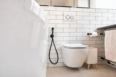Modern bathroom with wall-hung toilet, concealed cistern flush plate, white subway tiles, and black bidet spray.