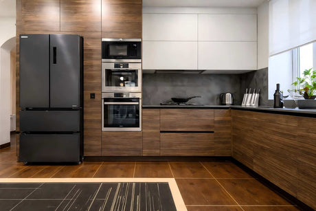 Modern L-shaped kitchen featuring sleek black appliances, wood panel cabinetry, and a dark stone countertop with a minimalist design.
