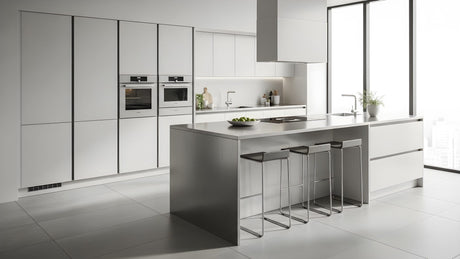 Contemporary minimalist kitchen with white cabinetry, built-in appliances, and a spacious breakfast bar island. 