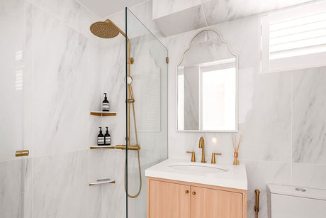 Modern bathroom with marble tiles, gold shower and wooden vanity
