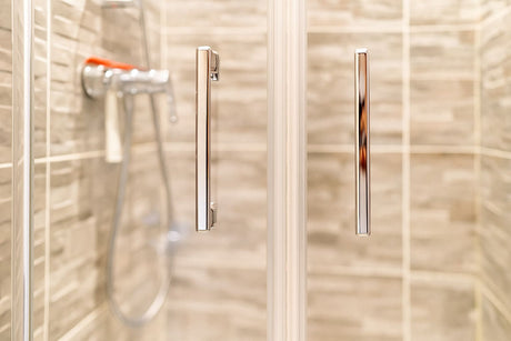 Close-up view of shower door handles with tiled background