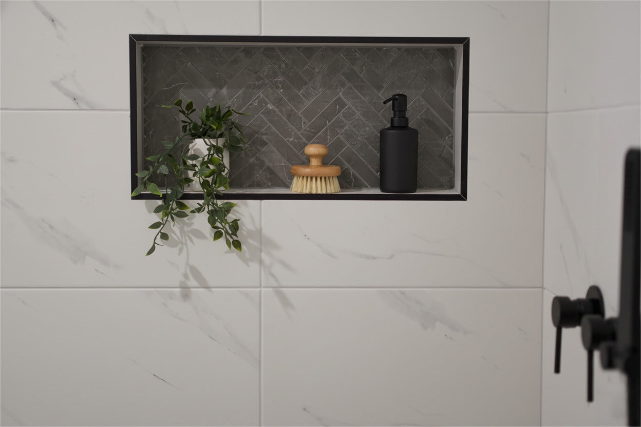 Shower niche with plants, brush, and black bottle in modern bathroom