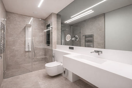 Modern minimalist bathroom with frameless glass shower, floating vanity, wall-hung toilet and grey stone tiles.