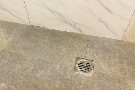 Shower floor with a drainage grate and marble wall