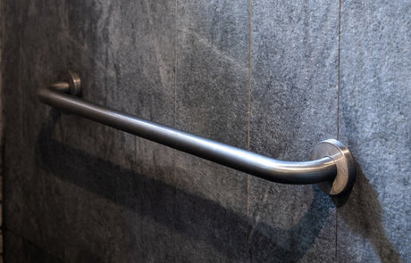 Stainless steel grab rail mounted on grey stone-look bathroom wall tiles