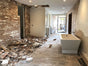 Bathroom renovation in progress with exposed brick wall, construction debris, and new freestanding bathtub