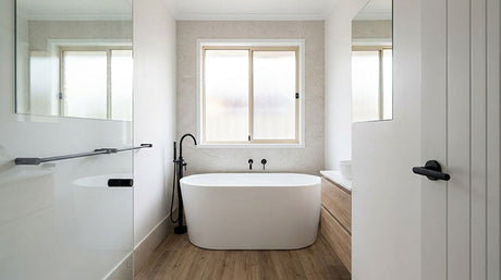 Modern bathroom with white freestanding bath, timber floor and matte black tapware