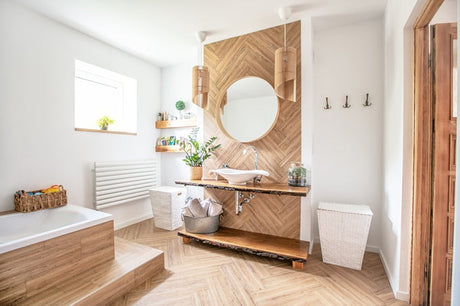 Bright bathroom with wood accent wall, round mirror, floating vanity, and bathtub