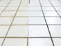 Bathroom floor tiles showing dirty grout compared to cleaned grout in before and after comparison