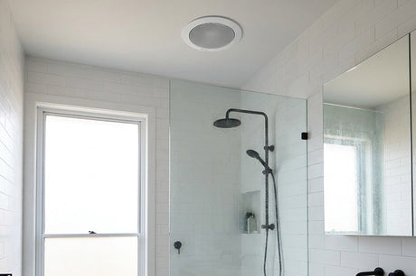Modern white tiled bathroom with ceiling exhaust fan, glass shower and timber vanity