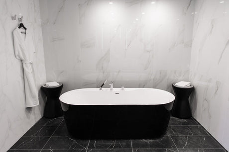 Black and white freestanding bathtub centred in marble-tiled luxury bathroom