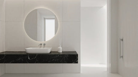 Minimalist bathroom with black marble vanity, white vessel basin and round backlit mirror