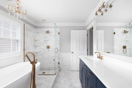 Beautiful bathroom with a blue vanity cabinet, standalone bathtub, and gold faucets in a luxury interior