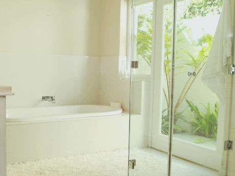 bright bathroom alcove bathtub beside glass door with natural garden view outside