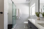 Bright modern bathroom with glass walk-in shower, white subway tile walls, patterned floor and natural light