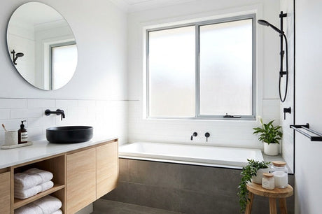Modern white bathroom with timber vanity, black basin, and built-in bath