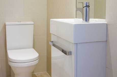 White close-coupled toilet with cistern beside compact wall-hung vanity and mirror