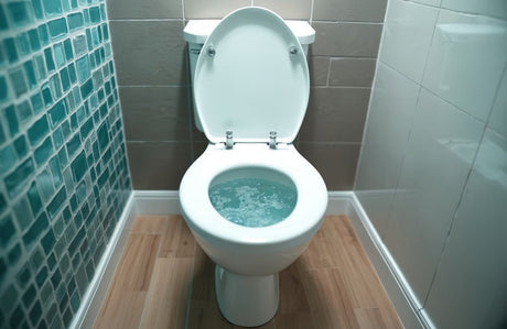 White toilet flushing with swirling water, teal mosaic and grey tiles behind