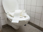 clogged toilet bowl overflowing with excess toilet paper in tiled bathroom