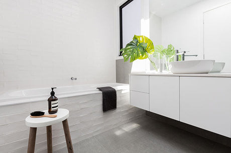 Modern white bathroom with built-in bath, floating vanity, and monstera plant