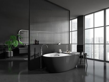 Dark modern bathroom with freestanding tub, ribbed glass wall, city view, and plant.