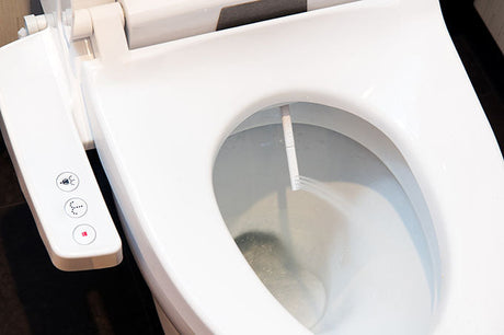 Electronic bidet toilet seat with control buttons installed in a modern bathroom