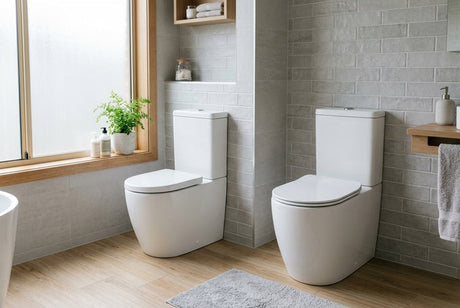Two white toilets in grey-tiled bathroom, one against timber-framed window