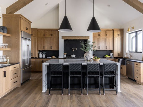 Modern kitchen with engineered wood flooring, large island, wood cabinets, black pendant lighting