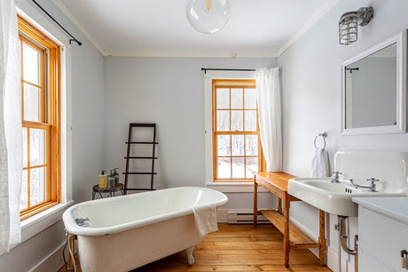 Farmhouse bathroom with clawfoot bath, timber floors, and white pedestal basin