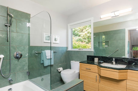 Modern bathroom with green wall tile, glass shower, and wood vanity