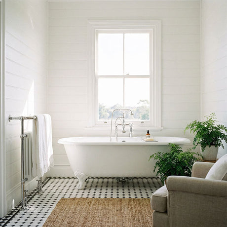 White Hamptons bathroom with clawfoot bath, black and white tile floor and fern