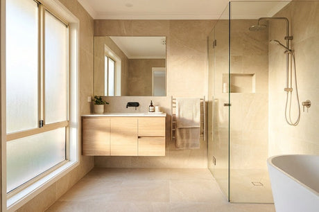 Modern bathroom with stone tiles, floating timber vanity, glass shower and freestanding bath