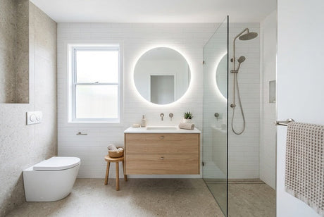 Modern bathroom with timber vanity, round backlit mirror, and glass shower