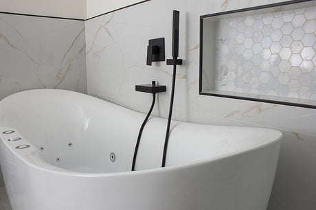 White freestanding spa bath with jets, matte black tapware and marble-look tiles