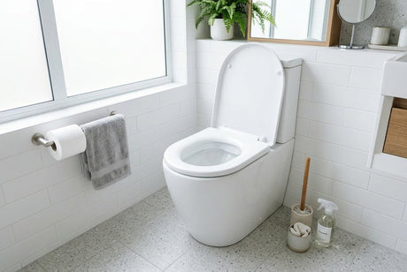 White toilet with open lid in bright tiled bathroom with grey towels
