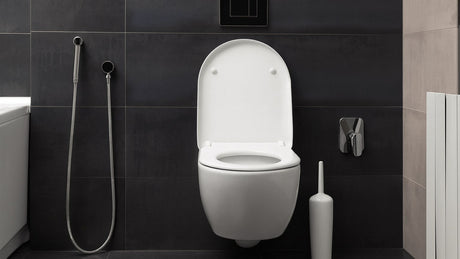 Modern wall-hung toilet with bidet spray on dark tiles
