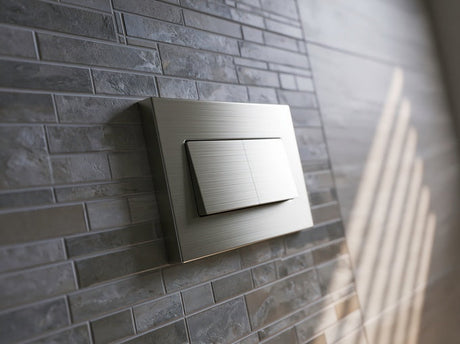 Brushed nickel in-wall cistern flush plate mounted on grey stone tiles